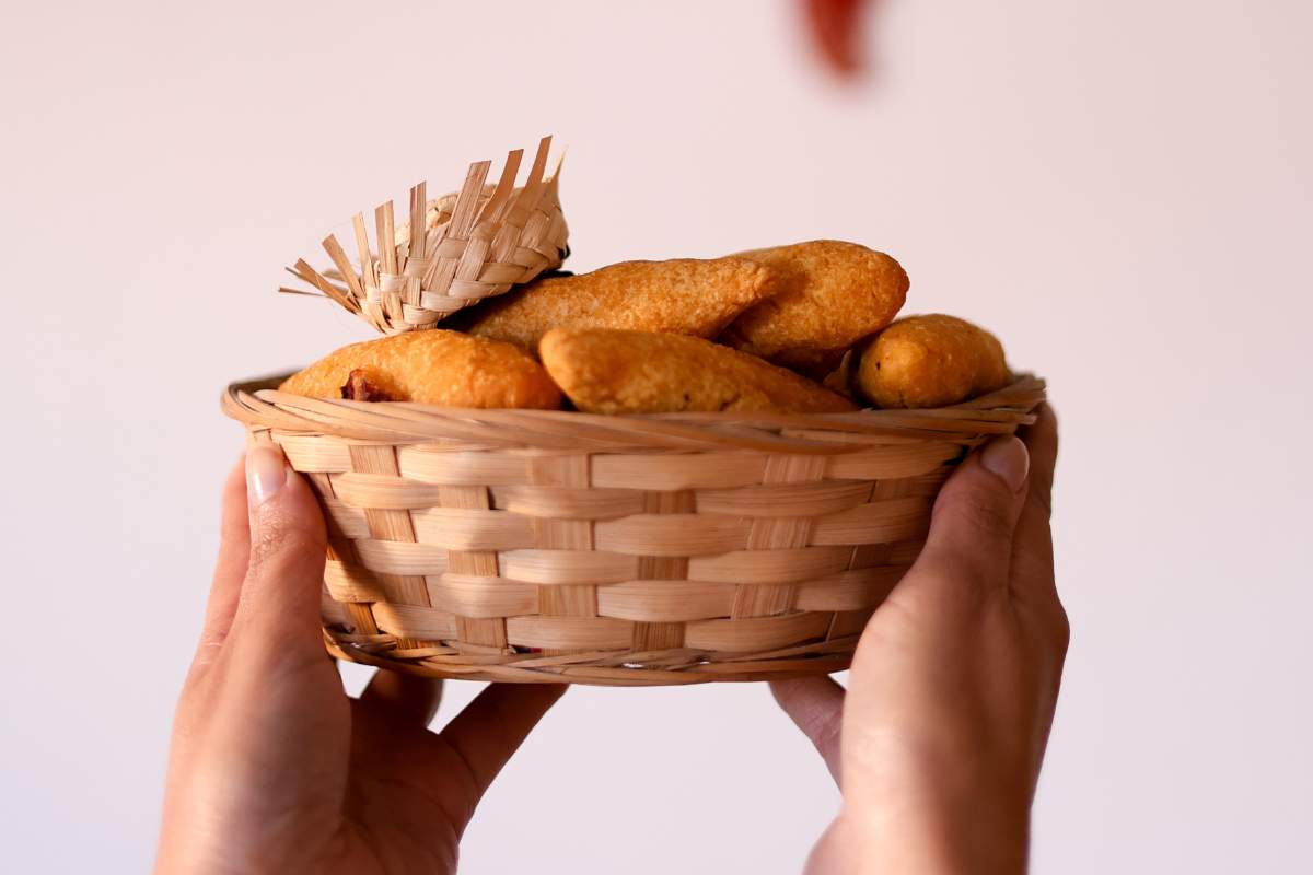Bolinho caipira tradicional com massa de farinha de milho e recheio de carne moída, dourado e crocante, servido em um prato.